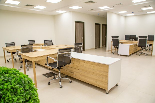 Spacious office interior with wooden desks and ergonomic chairs, perfect for a productive workday.