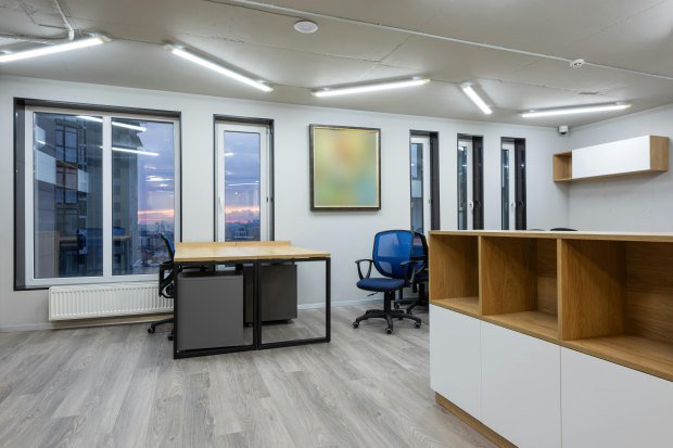 Interior of office with contemporary new wooden tables and chairs glowing by ceiling lamps