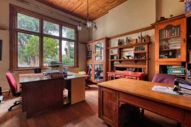 Warm and inviting traditional home office featuring vintage wooden furniture and large windows with garden view.