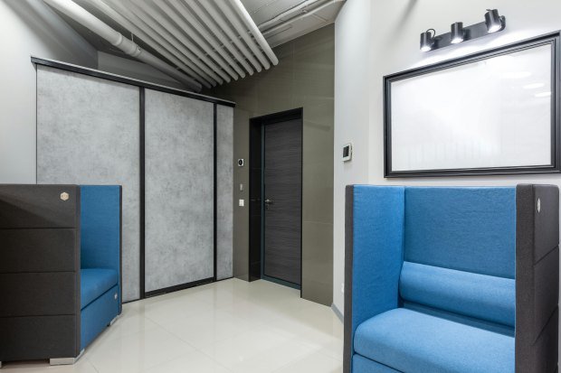 Modern Interior of office lobby with soft blue armchairs and entrance door near built in wardrobe