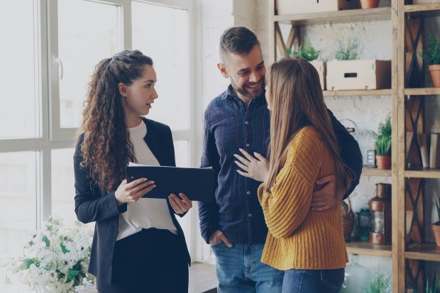 A couple consulting with a real estate agent in a cozy office setting with indoor plants.